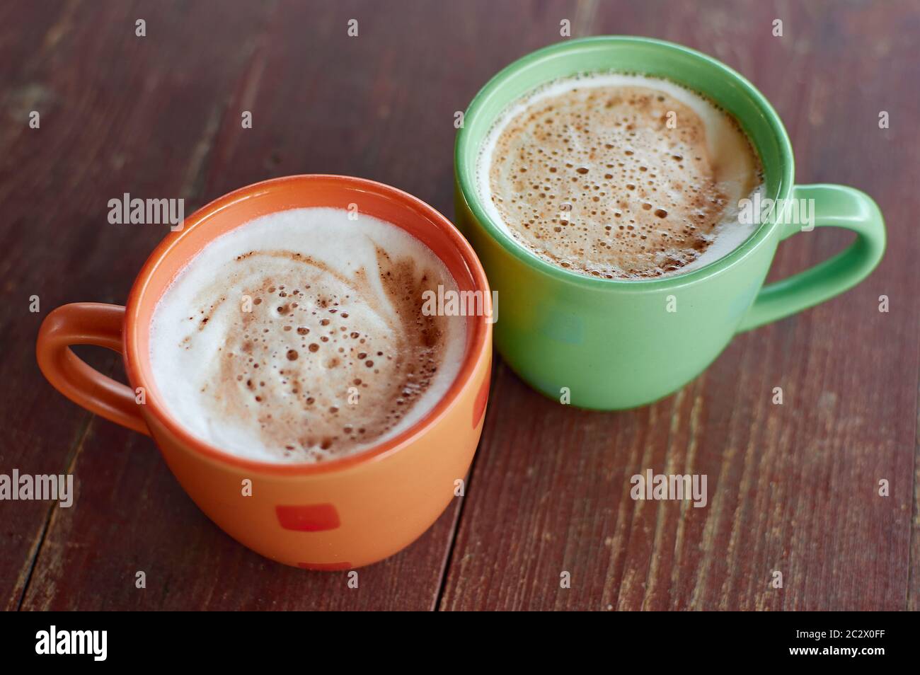 Due tazze di cappuccino profumato su una carta da copertura in legno. Schiuma di latte ariosa di una bevanda calda. Bevanda a base di caffè con latte Foto Stock