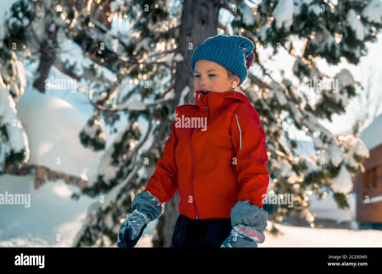 Bambina che si gode vacanze invernali, grazioso bambino vestito con abiti caldi divertirsi all'aperto sul cortile e giocare con la neve, felice vacanza invernale Foto Stock