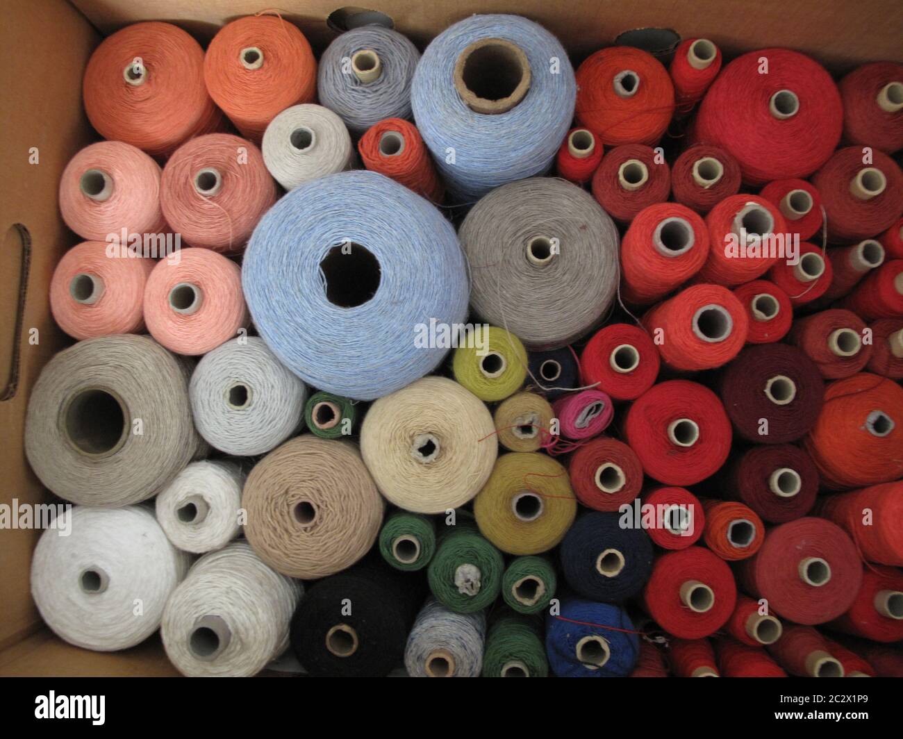gran gruppo di filati di cotone e lino nei colori rosso, salmone, bianco, beige, grigio fumo, marrone, blu chiaro, verde, arancio, rosso vino, nero e. Foto Stock