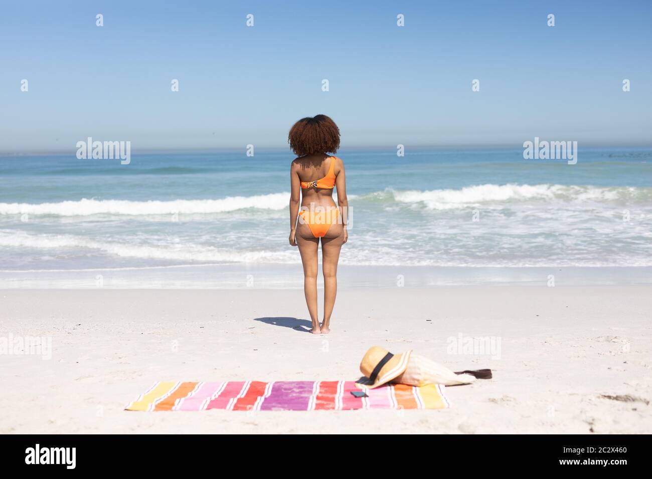 Donna afroamericana in piedi sulla spiaggia Foto Stock