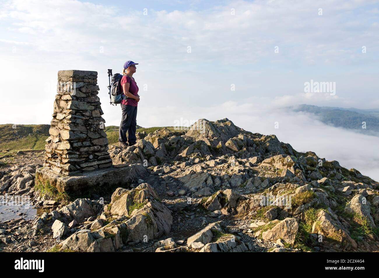 Walker godendo della vista dalla cima di Loughrigg cadde sulle valli piene di nube, Lake District, Cumbria, UK Foto Stock