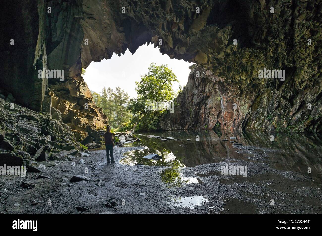 Walker all'interno delle grotte di cava Rydal, Loughrigg Fell, Lake District, Cumbria, Regno Unito Foto Stock