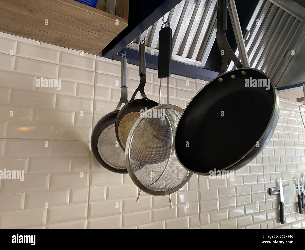 set di utensili da cucina appesi alla parete di lucidatura in calcestruzzo grezzo per ogni uso in cucina Foto Stock