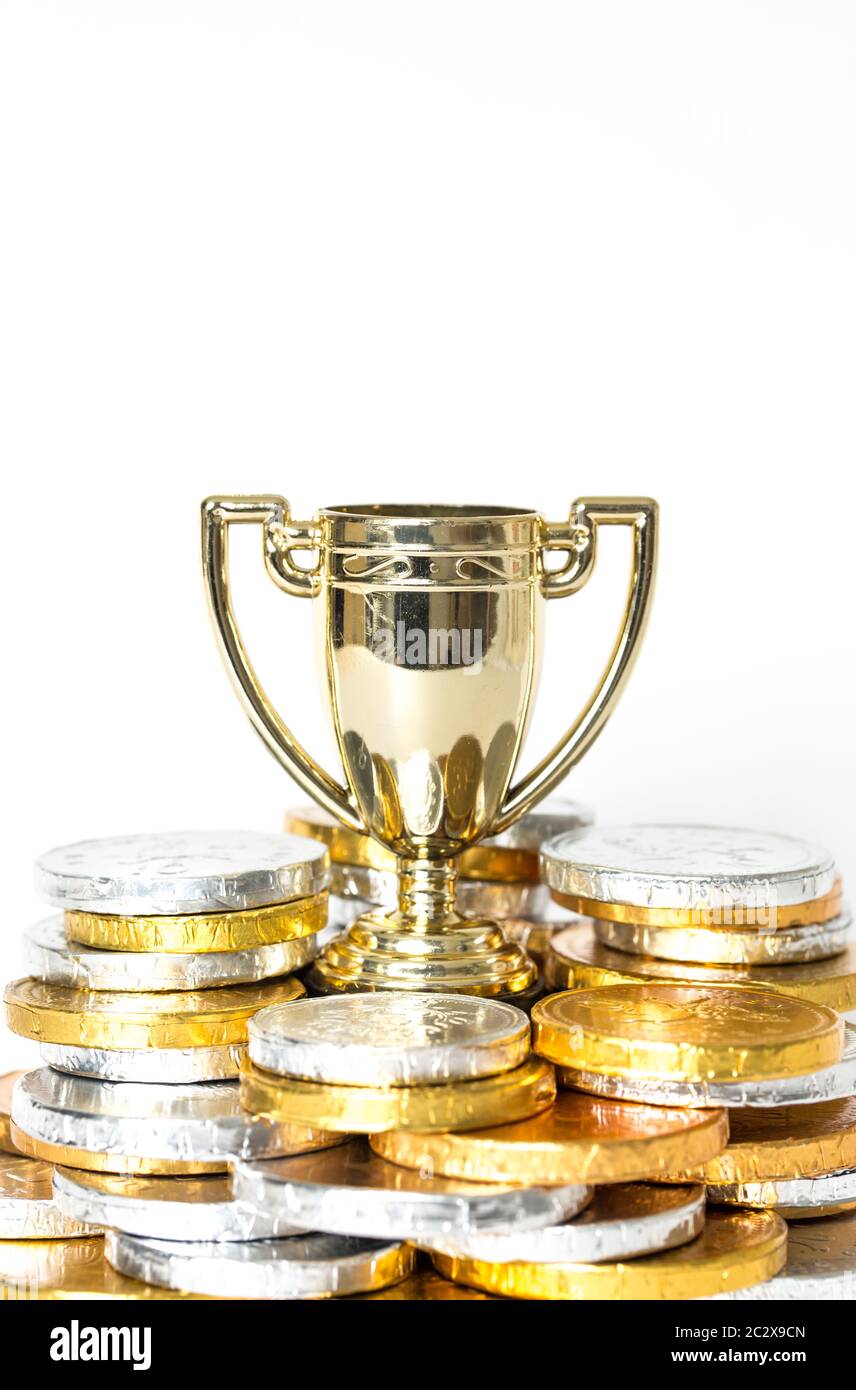 Un concetto di successo o vittoria con un trofeo o una coppa d'oro circondati da monete d'oro e d'argento sotto forma di premi in denaro Foto Stock