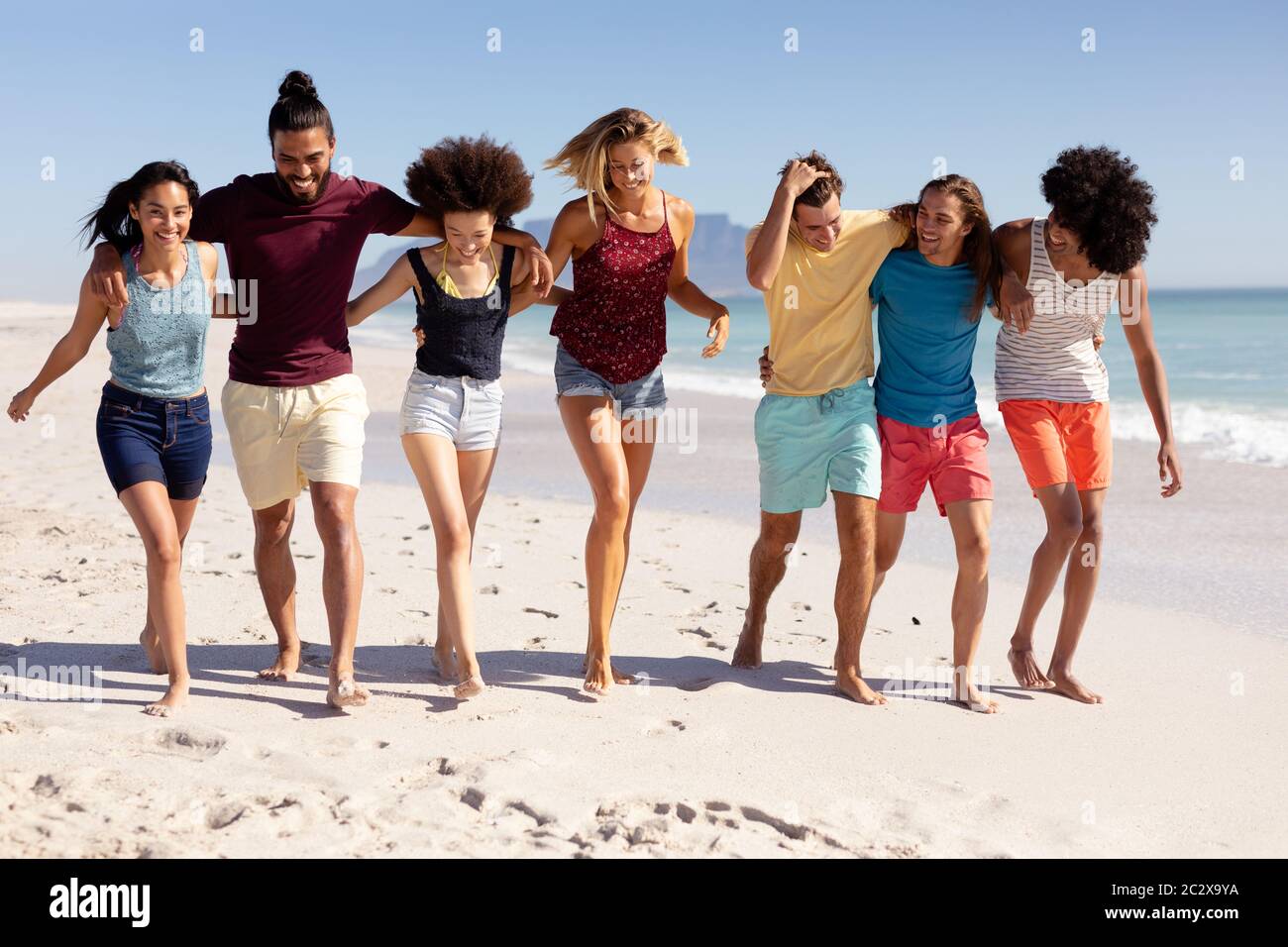 Gruppo multietnico di uomini e donne in piedi sulla spiaggia Foto Stock