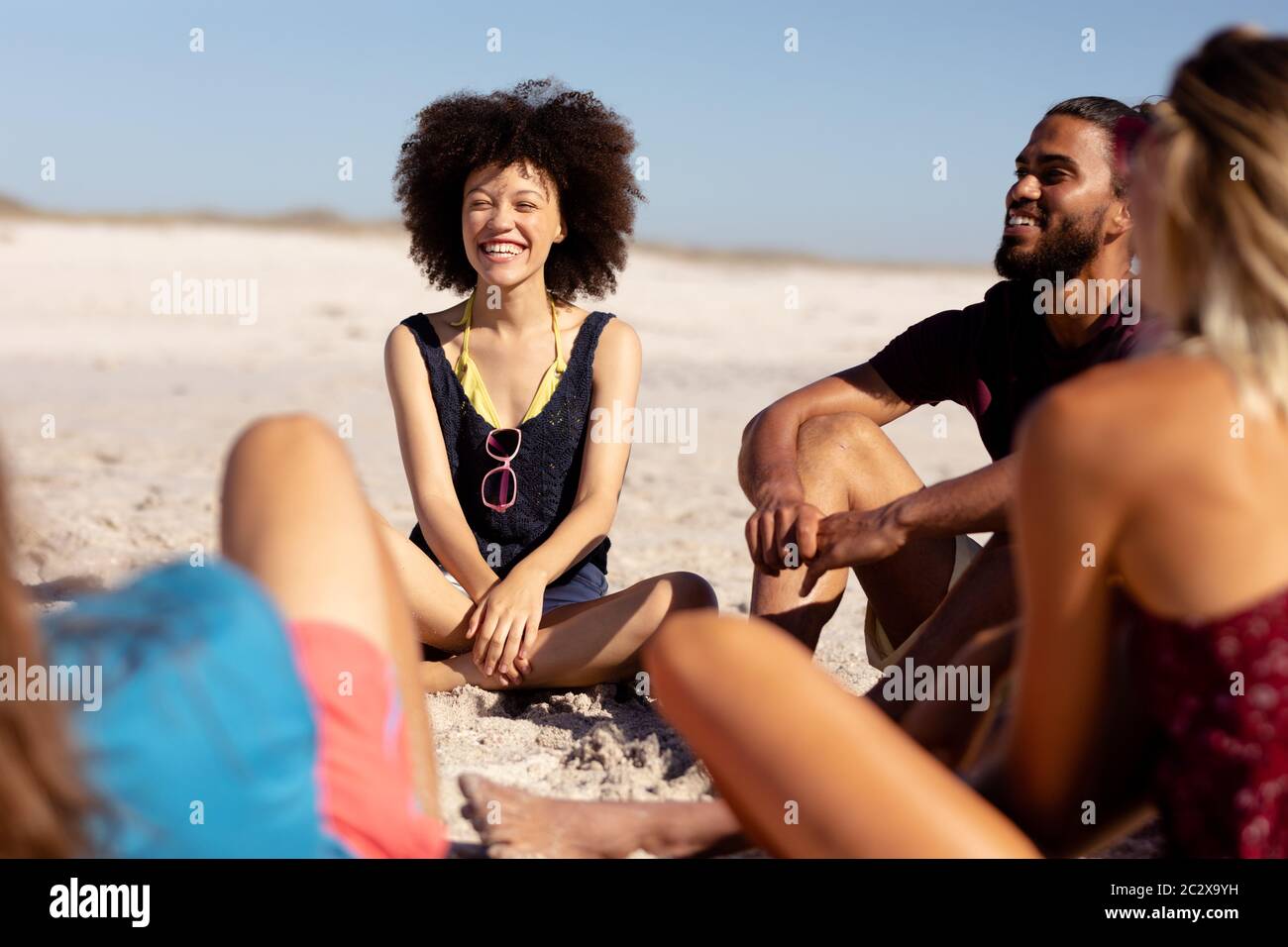 Gruppo multietnico di uomini e donne seduti sulla spiaggia Foto Stock