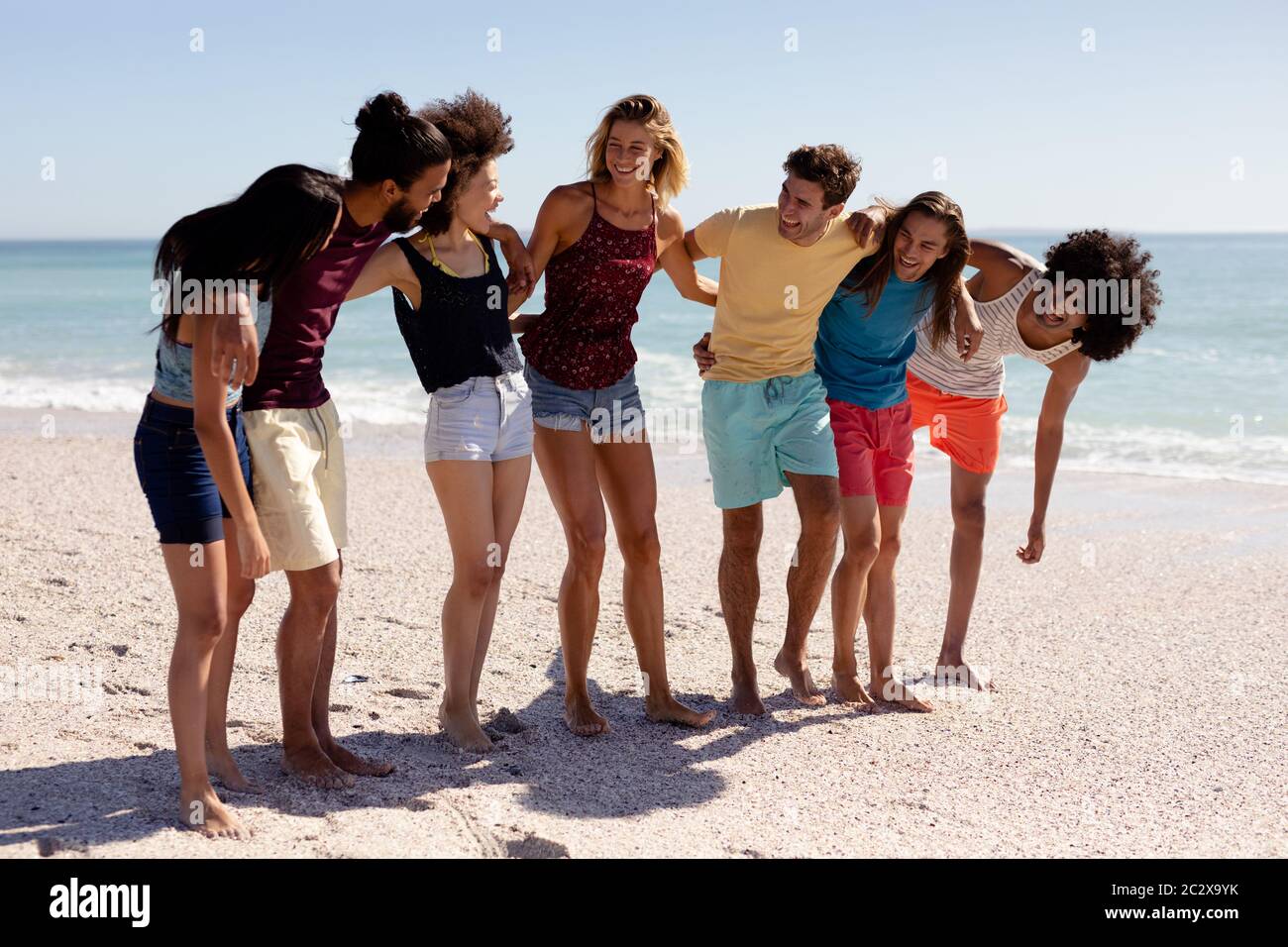 Gruppo multietnico di uomini e donne in piedi sulla spiaggia Foto Stock