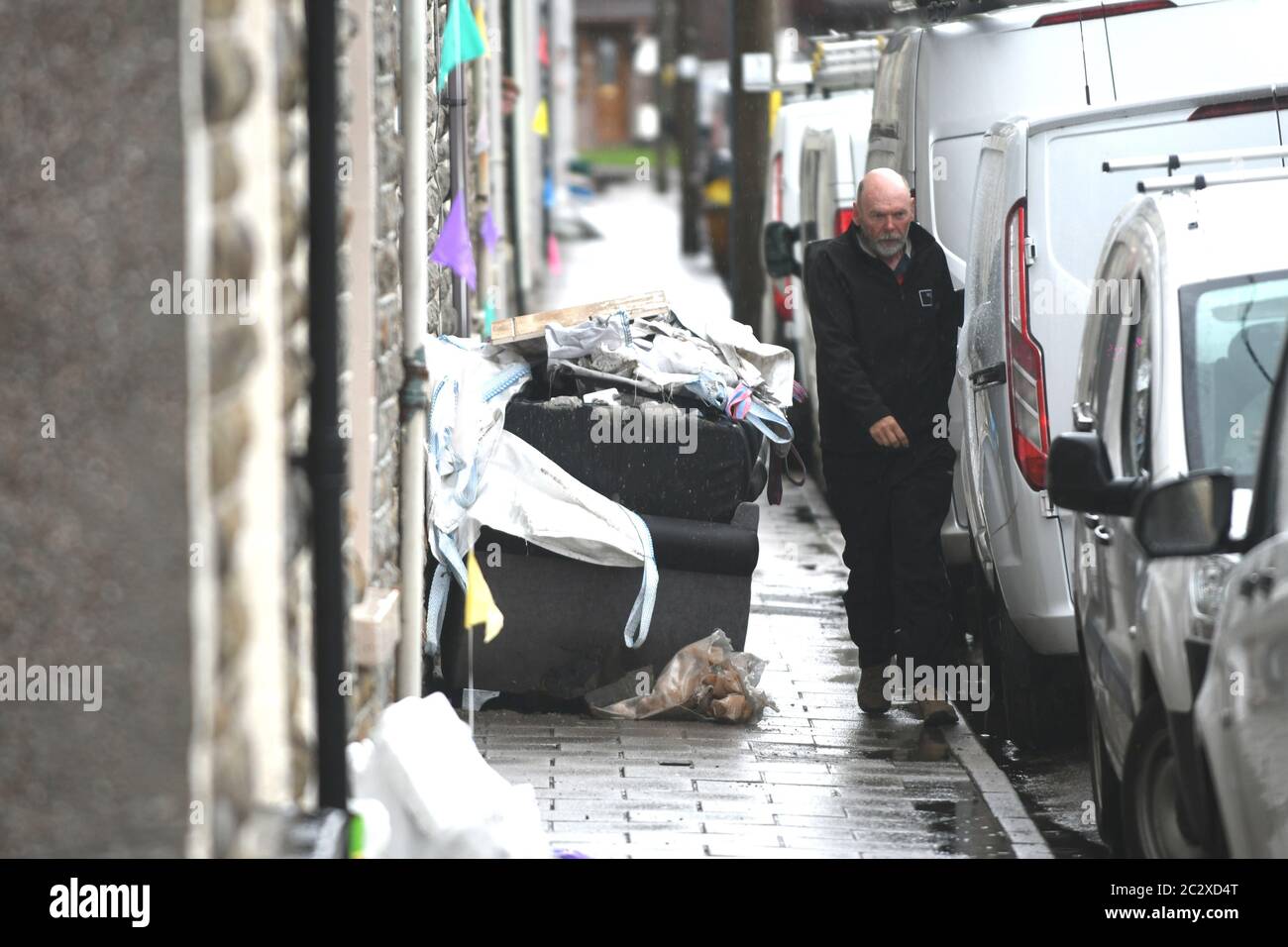 Rhondda, Galles 18 giugno 2020. Tempo nel Regno Unito : UN uomo strizza i rifiuti passati da una casa a Pentre, Rhondda Valley nel Galles del Sud, che è stata colpita da inondazioni in flash dopo forti piogge nella zona. È la seconda volta che quest'anno i residenti sono stati colpiti dalle inondazioni, distruggendo le case e portando molti a trovare nuove sistemazioni. Credit : Robert Melen/Alamy Live News Foto Stock