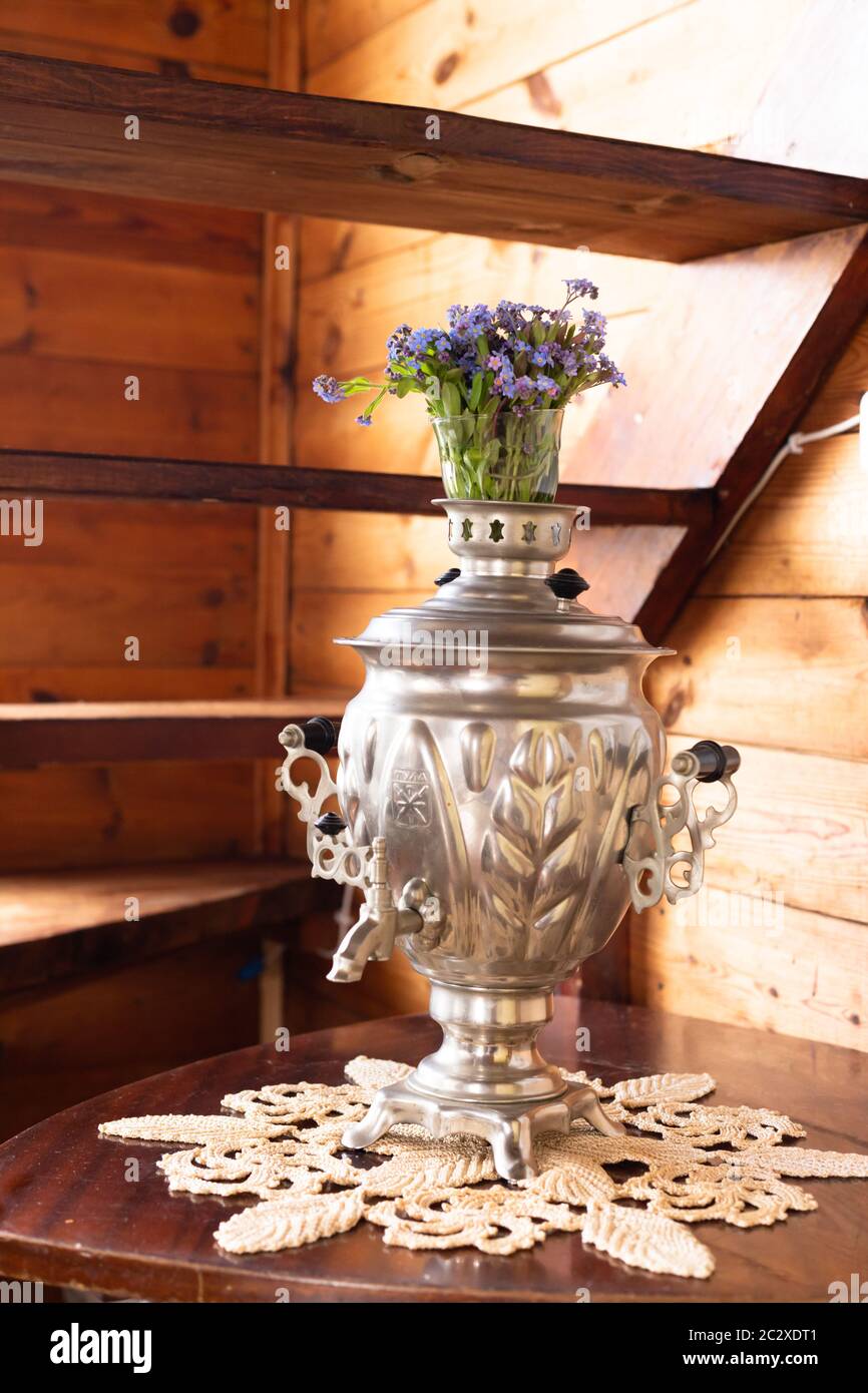 Samovar in metallo antico e bouquet di fiori blu su sfondo di legno Foto Stock