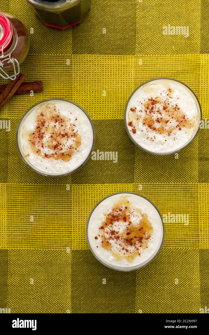 Dessert al budino di riso al cocco con frizzle di sidro d'acero sulla parte superiore e cannella cosparsa servita in una ciotola di vetro. Vista dall'alto. Foto Stock