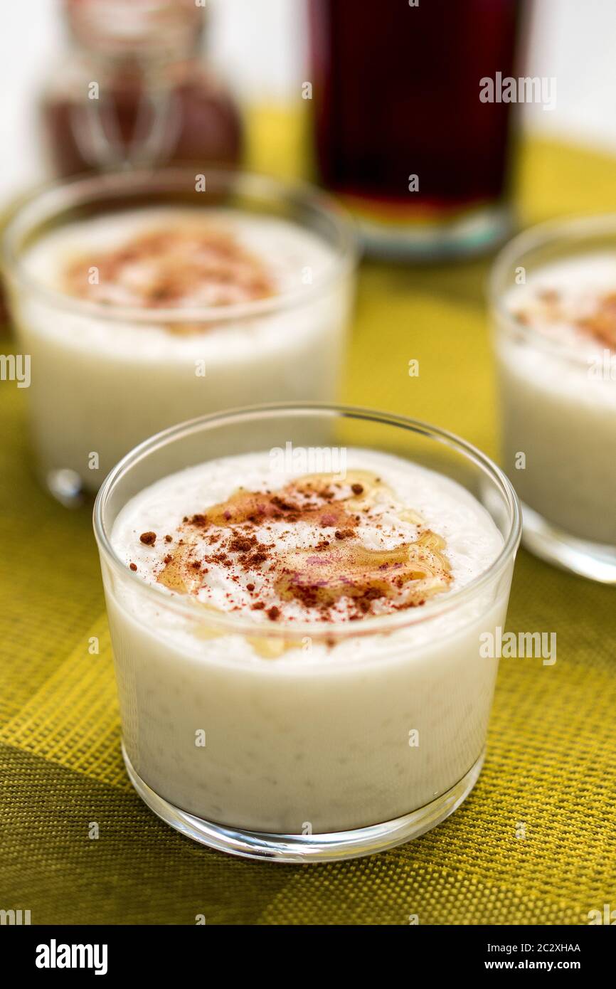 Dessert al budino di riso al cocco con frizzle di sidro d'acero sulla parte superiore e cannella cosparsa servita in una ciotola di vetro. Orientamento verticale. Foto Stock