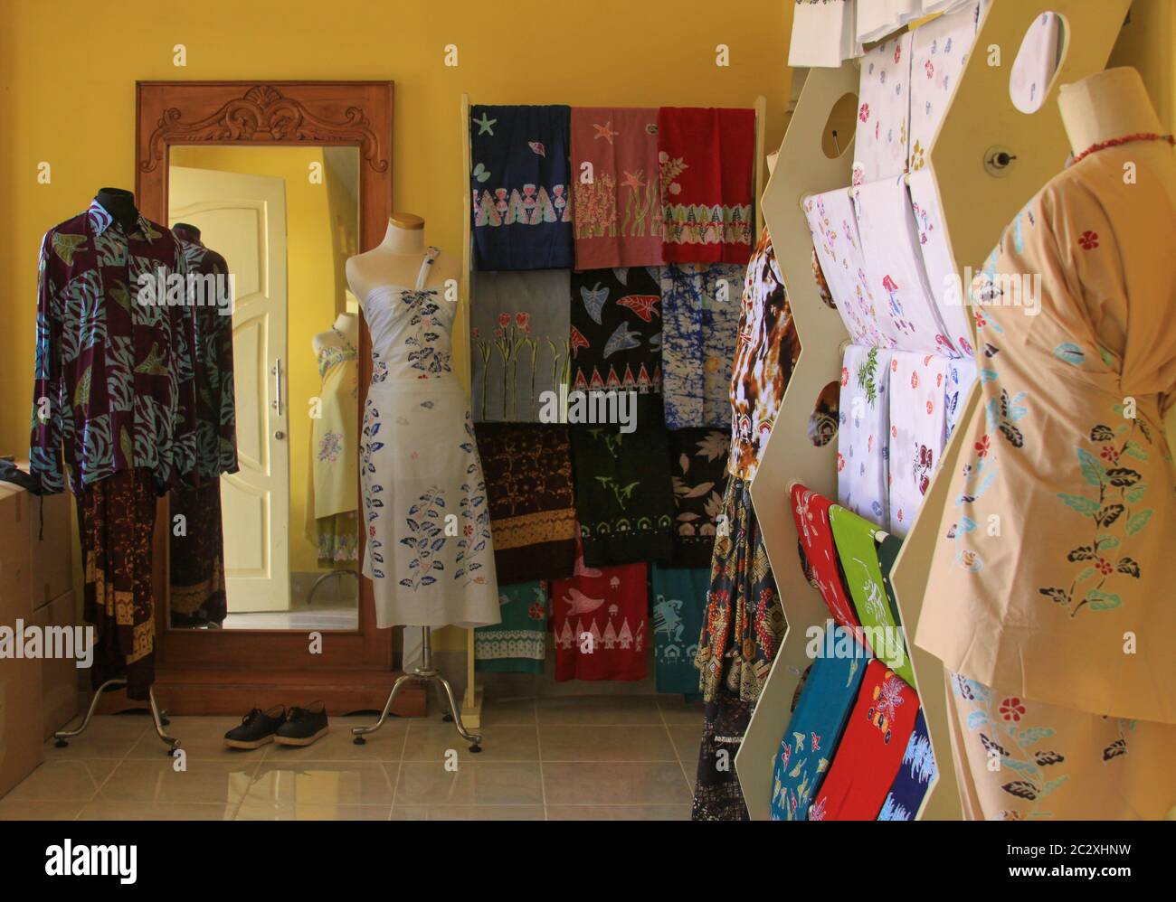 Negozio di tessuti batik a Mataram, Lombok, Indonesia. Diversi tipi di stoffa appesi e vestiti su manichini davanti allo specchio. Foto Stock