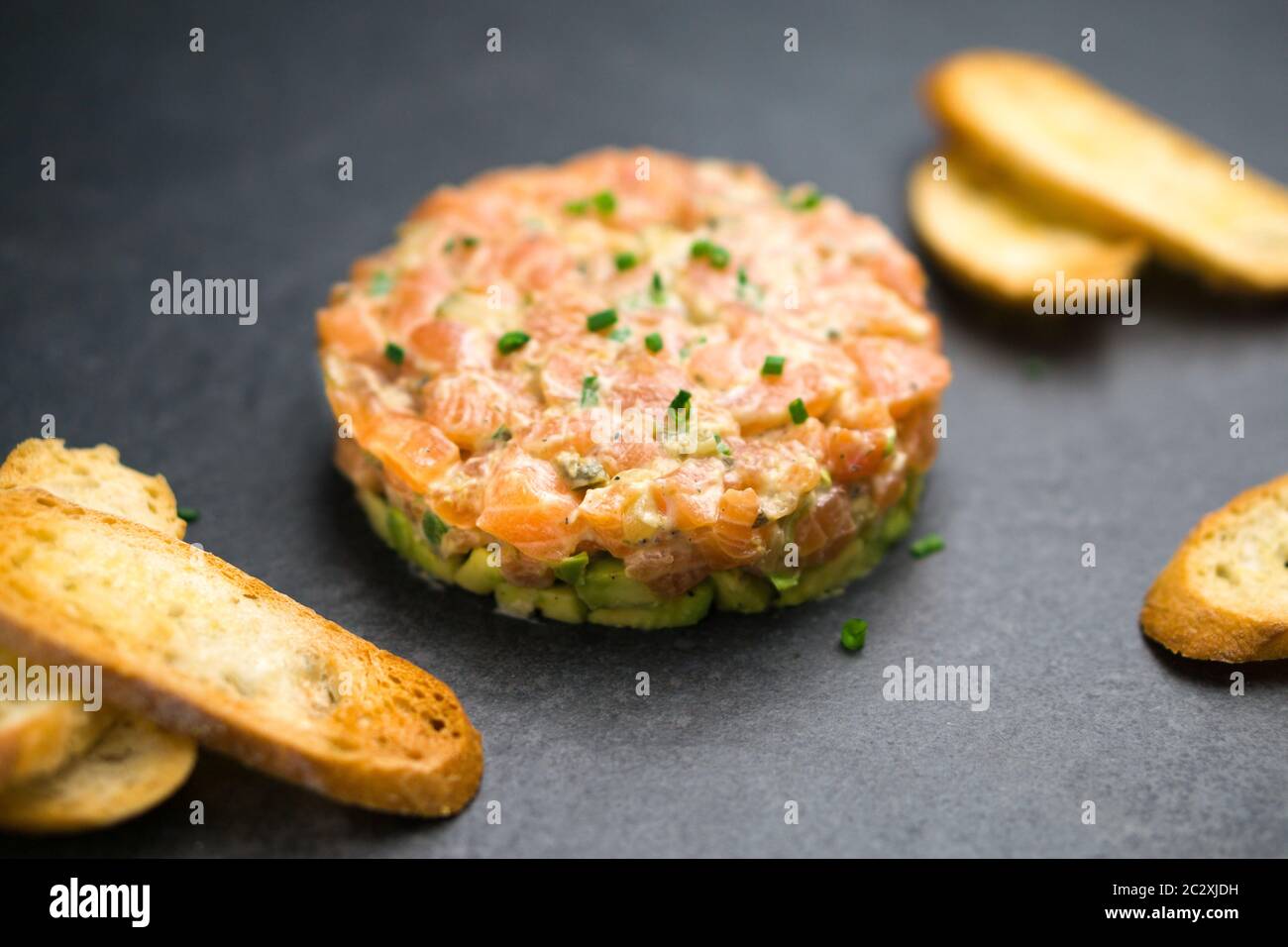 La tartare di salmone è preparata con pesce fresco fresco e crudo di salmone, avocado, salsa tartaro e cracker o pane. Questo piatto sano è spesso servito come antipasto Foto Stock