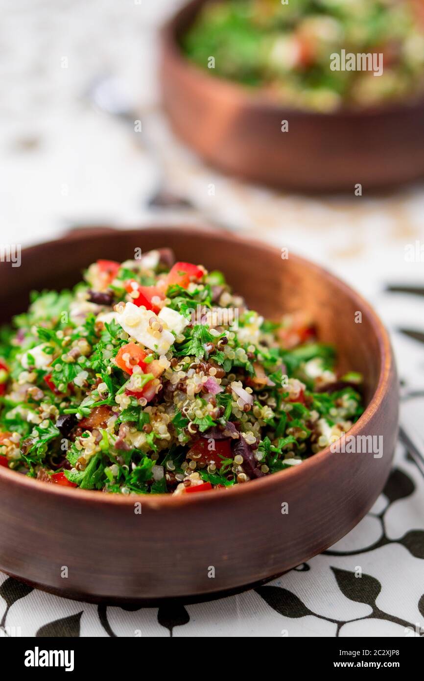 Piatto di quinoa per insalata. Questo piatto sano mescola tabbouleh e insalate in stile greco, utilizzando erbe fresche di prezzemolo, olive, cipolle, feta ecc. Foto Stock