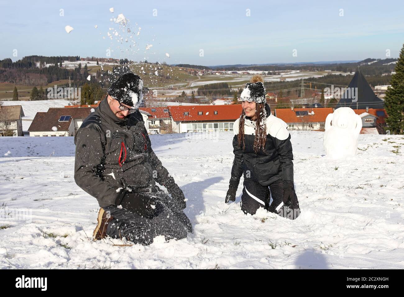 Una giovane coppia ha una lotta con la palla di neve in inverno. Una donna e un uomo si divertono nella neve Foto Stock