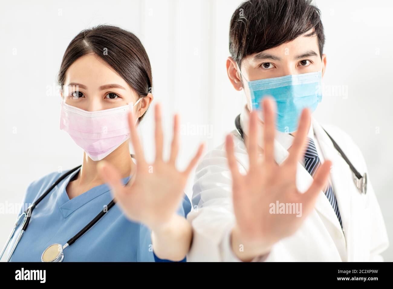 medico in maschera facciale e che mostra segno di stop con le mani Foto Stock