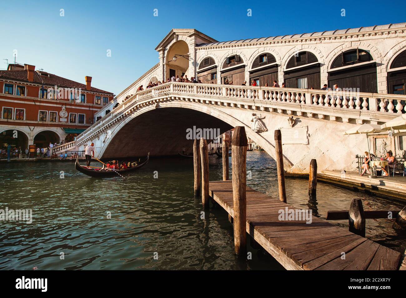 Gondola passando sotto il Ponte di Rialto durante il tramonto, che è il più antico dei quattro ponti che attraversano il Canal Grande di Venezia, Italia Foto Stock