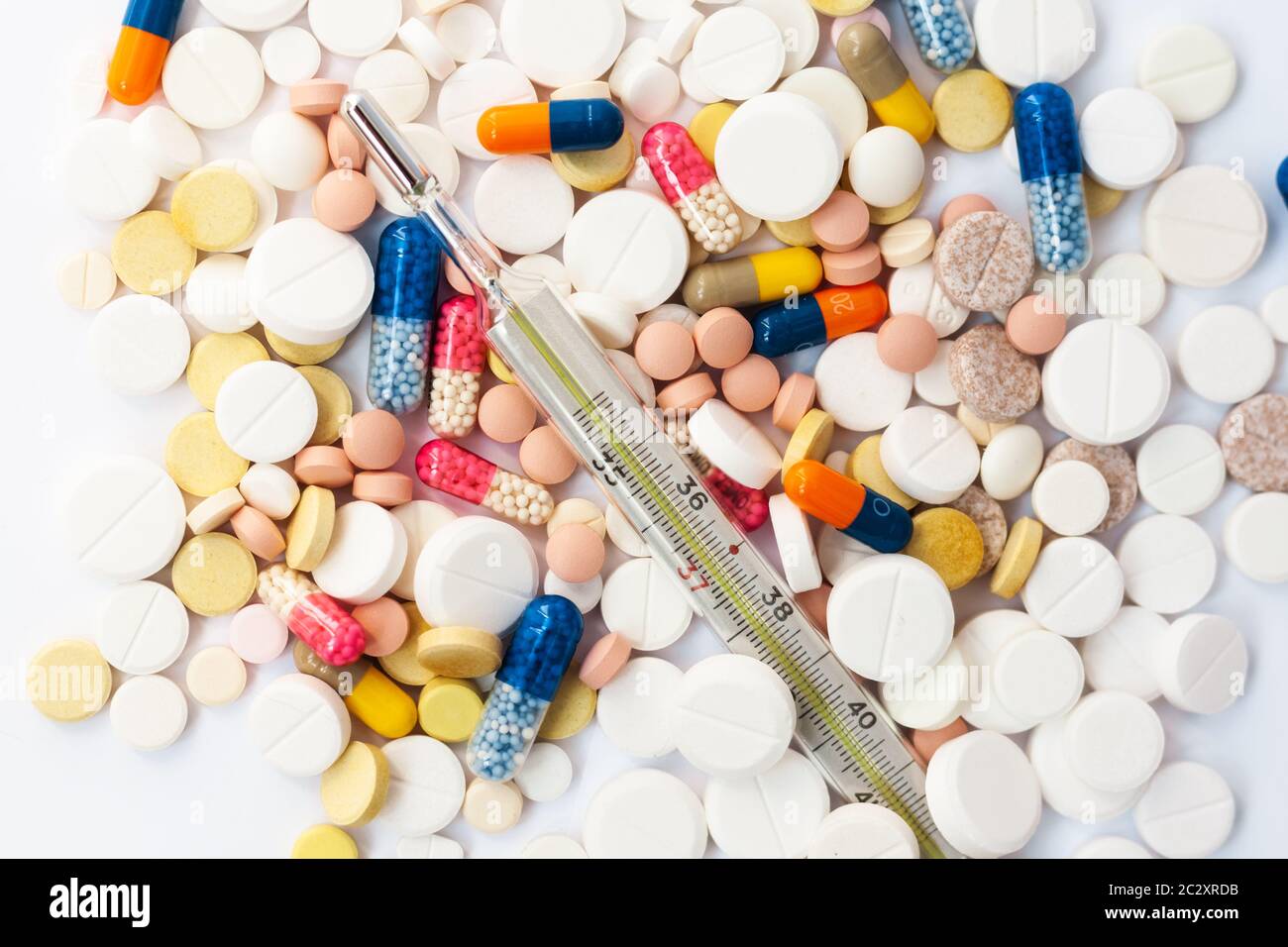 Termometro e pillole, medicina per polmonite, antibiotici su sfondo rosa. Coronavirus, MERS-cov, coronavirus Wuhan 2019-nCoV, concetto di Corona Foto Stock