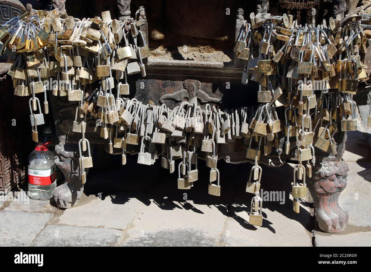 Immagine che mostra lucchetti di ottone legati ad un vecchio bruciatore di incenso arrugginito, all'interno di un tempio. La gente lascia i lucchetti qui come gettoni di gratitudine per il wis Foto Stock