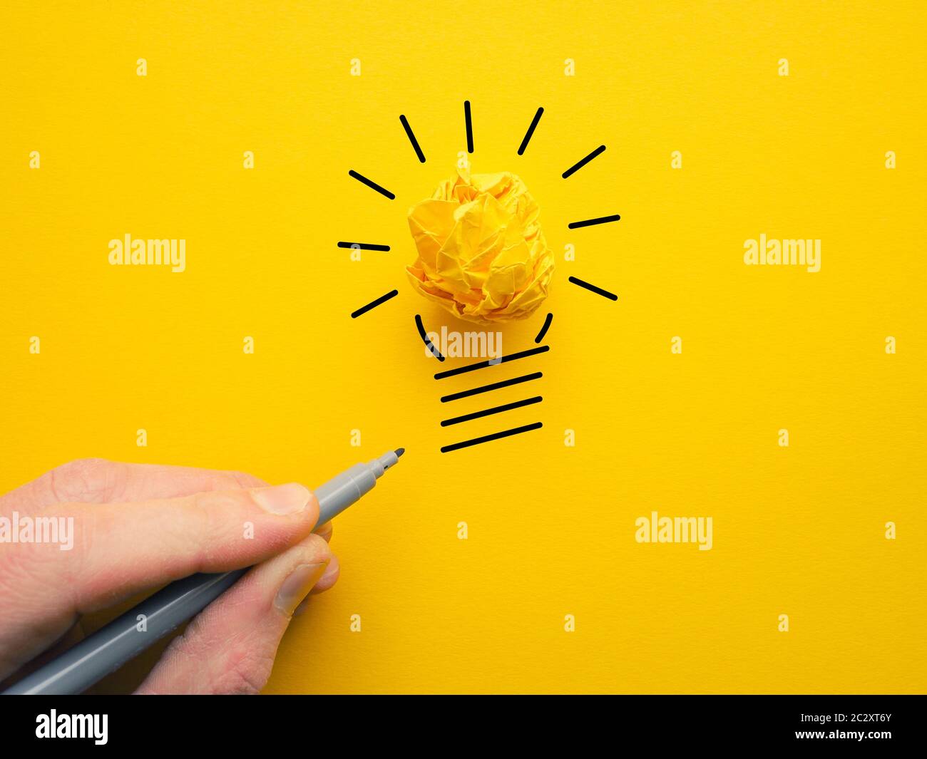 Uomo d'affari che disegna una lampadina, immagine concettuale di affari per le nuove idee o creatività, palla di carta crumpled gialla Foto Stock