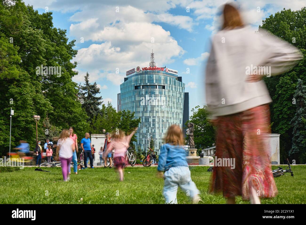 Bucarest, Romania - 1 giugno 2020: Intervallo di tempo per le persone che si godono una giornata di sole nel parco Herastrau, seduti in erba accanto alle biciclette, rilassarsi nel SM Foto Stock