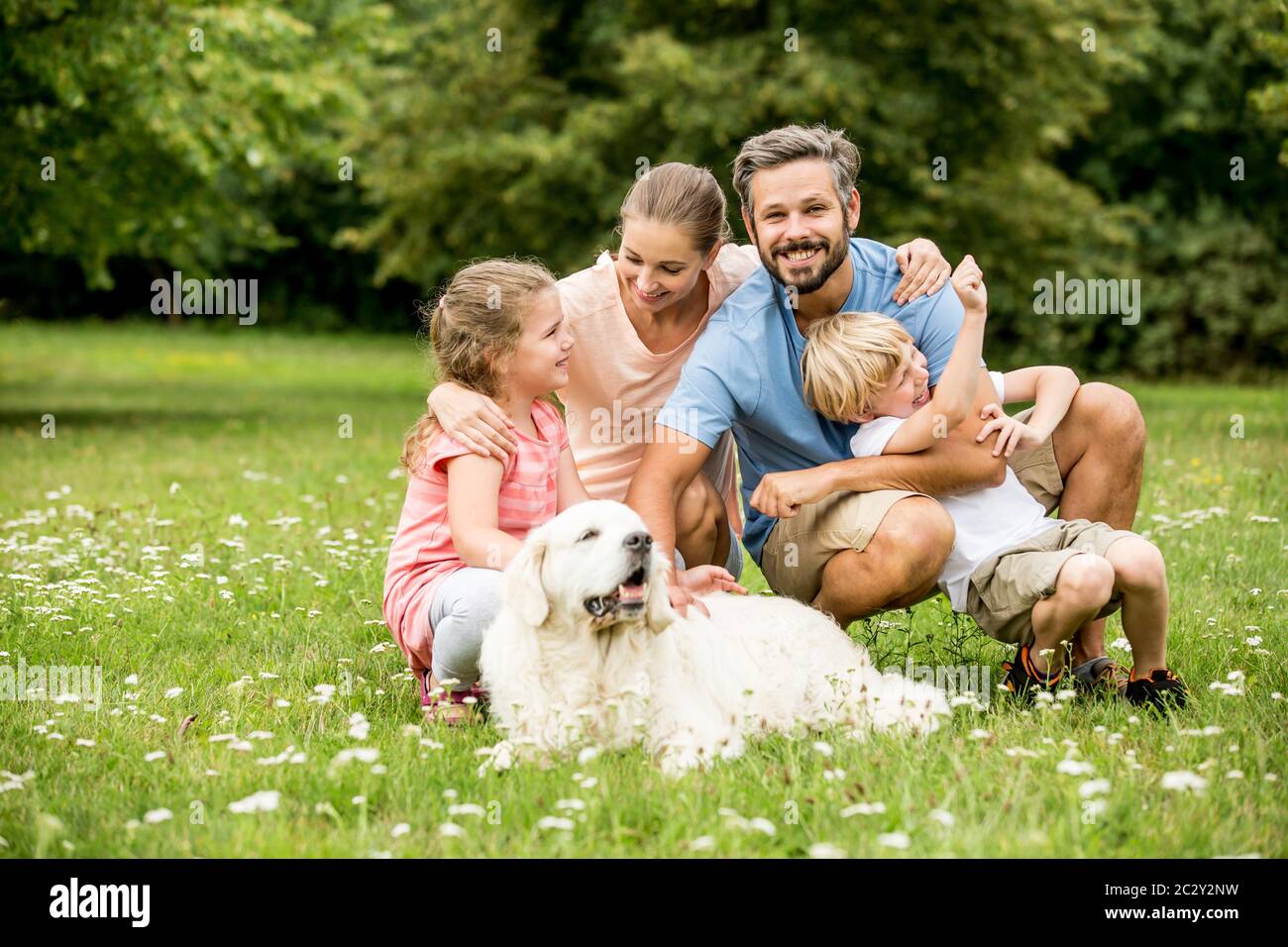 Famiglia felice con bambini e cane insieme in giardino in estate Foto Stock