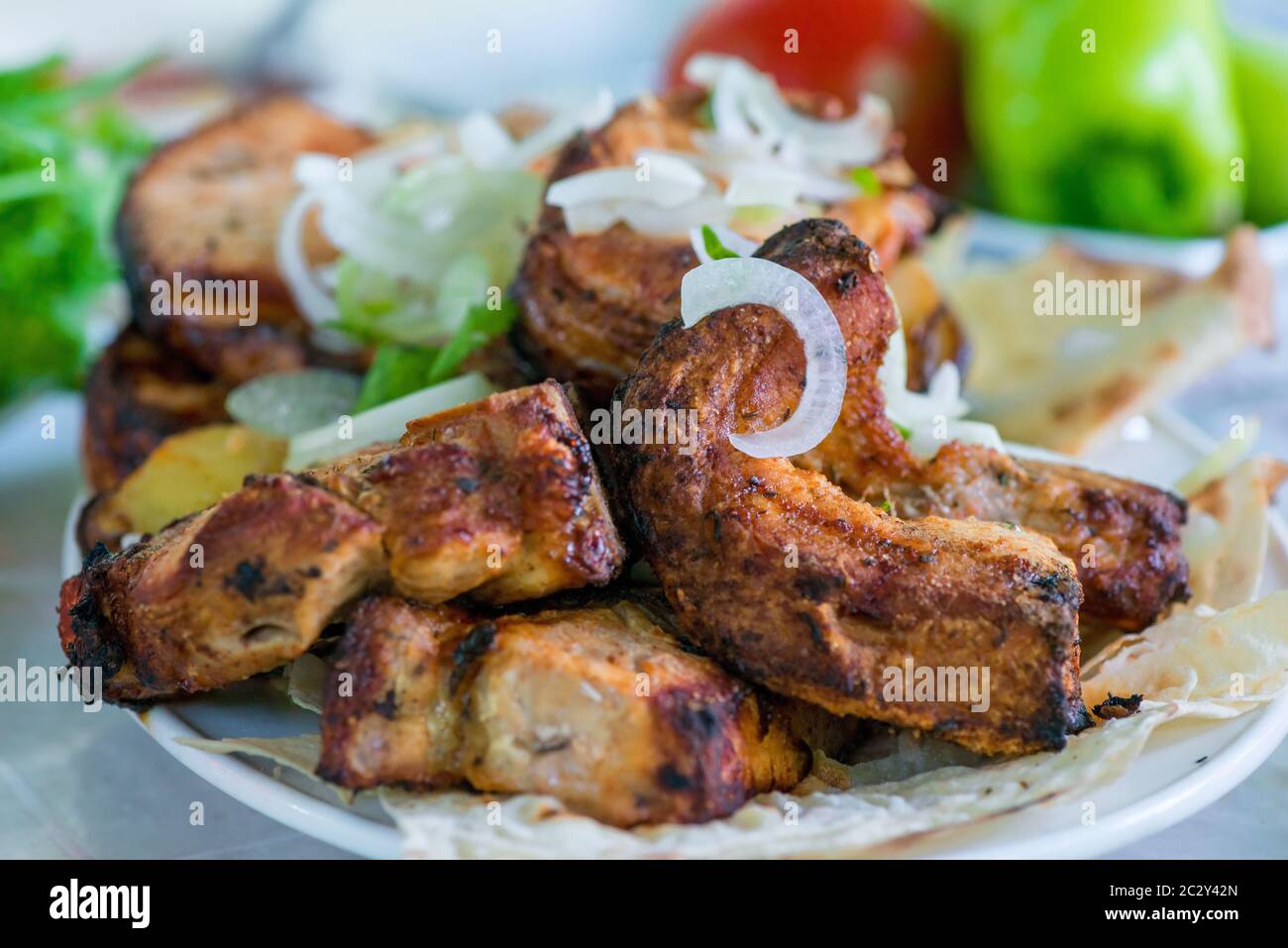 Spiedini di maiale con verdure e cipolle su un piatto Foto Stock