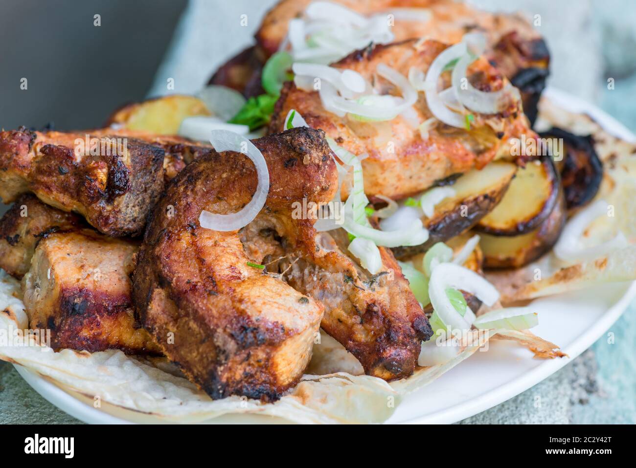 Appetitosi spiedini di maiale alla griglia con cipolle su un piatto Foto Stock