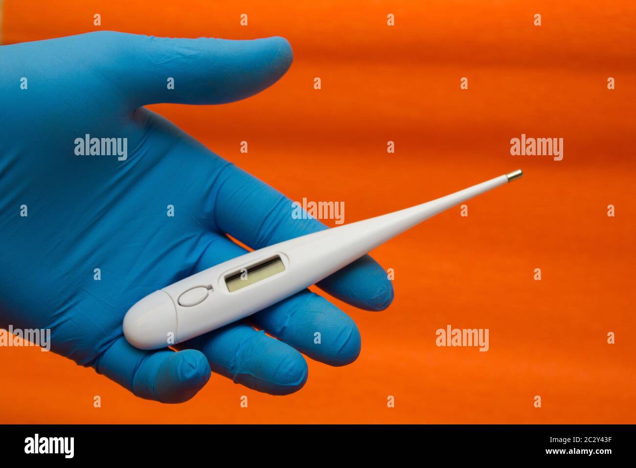 Mano in un guanto medico contiene un termometro elettronico - misurazione della temperatura, coronavirus, covid19 Foto Stock