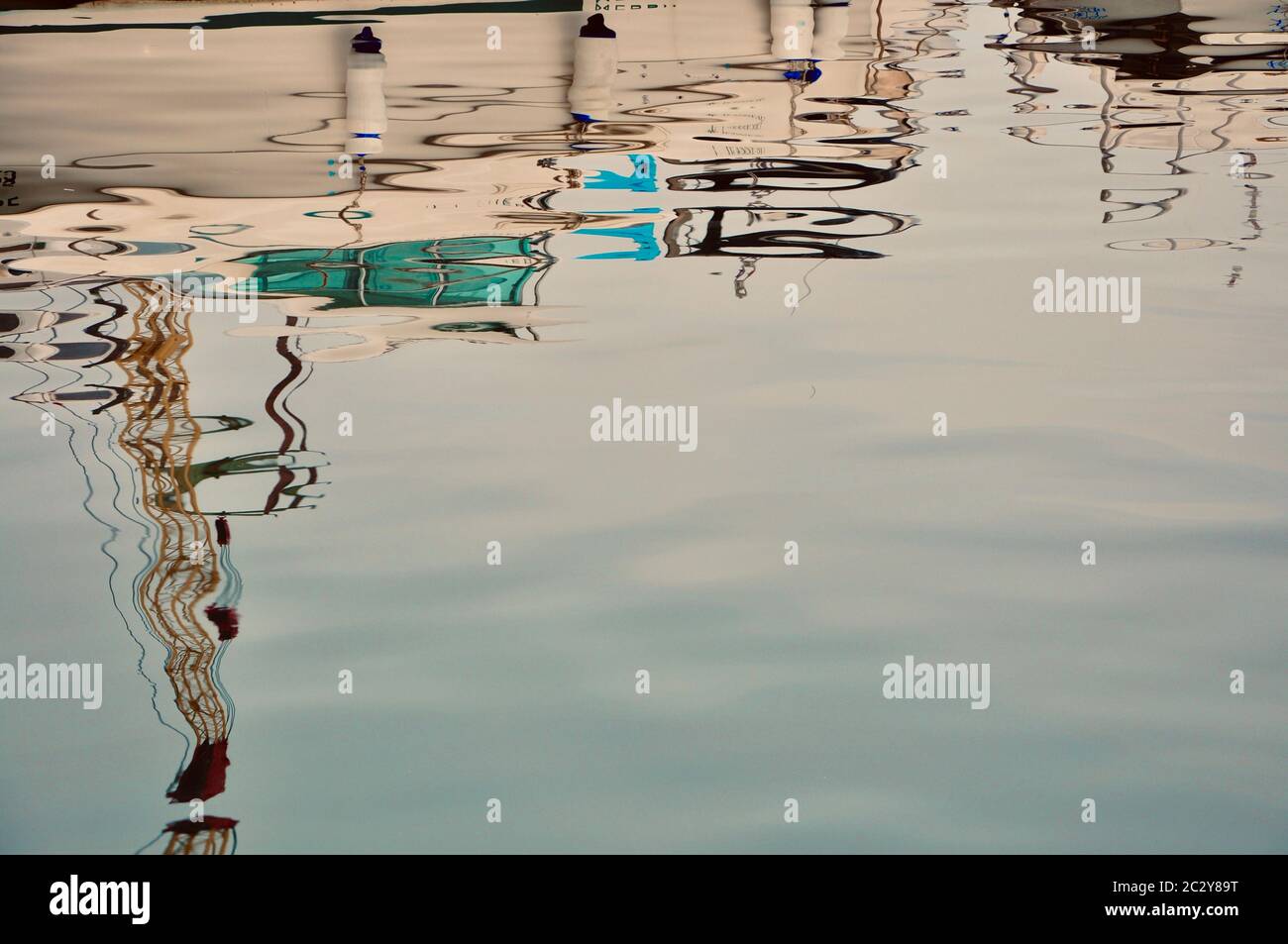 Riflessione astratta di barche a vela colorate che si mast su una superficie d'acqua increspata. Linee astratte di riflessione sul mare. Foto Stock