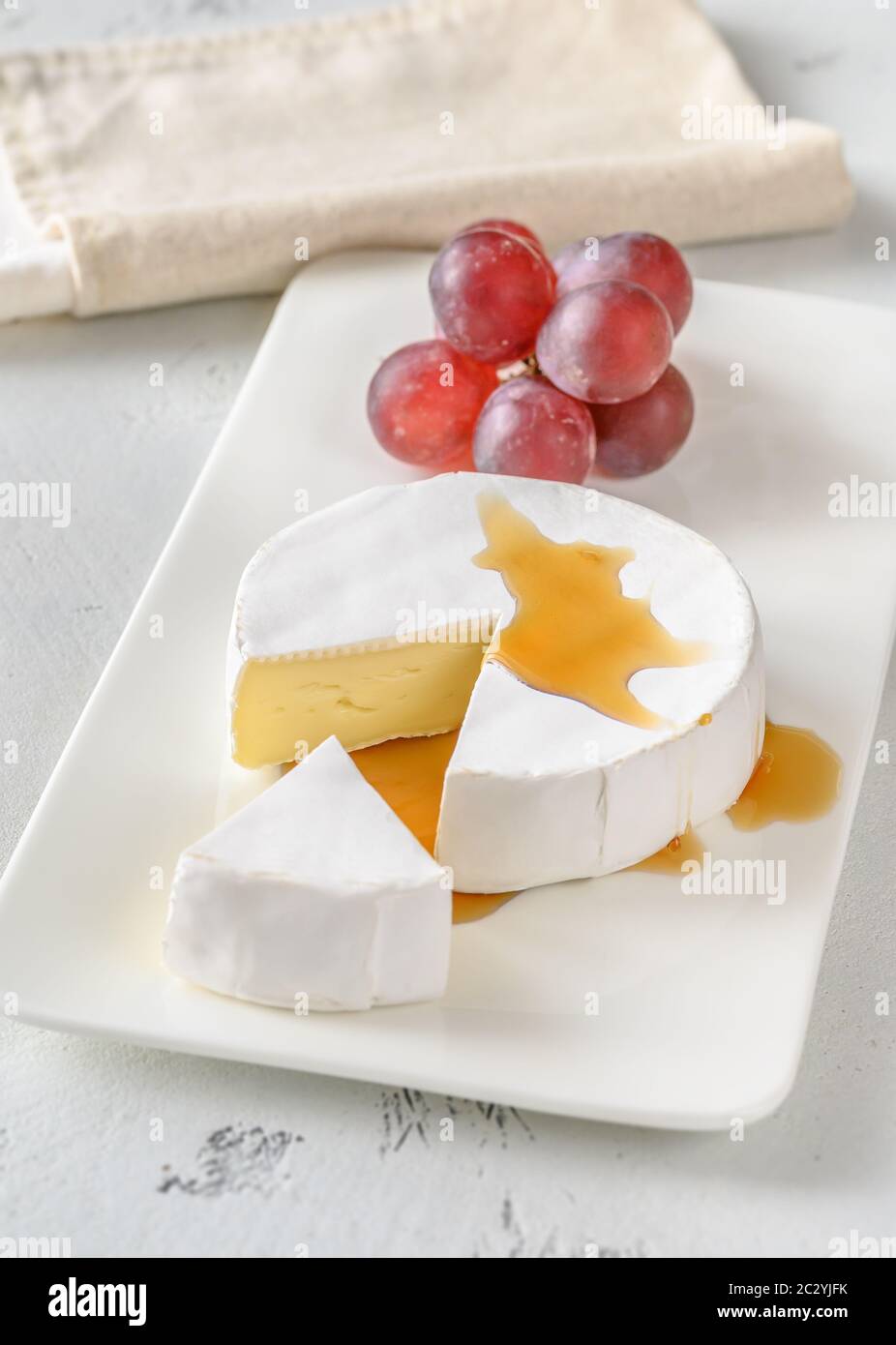 Camembert con grappolo d'uva sul piatto di servizio Foto Stock