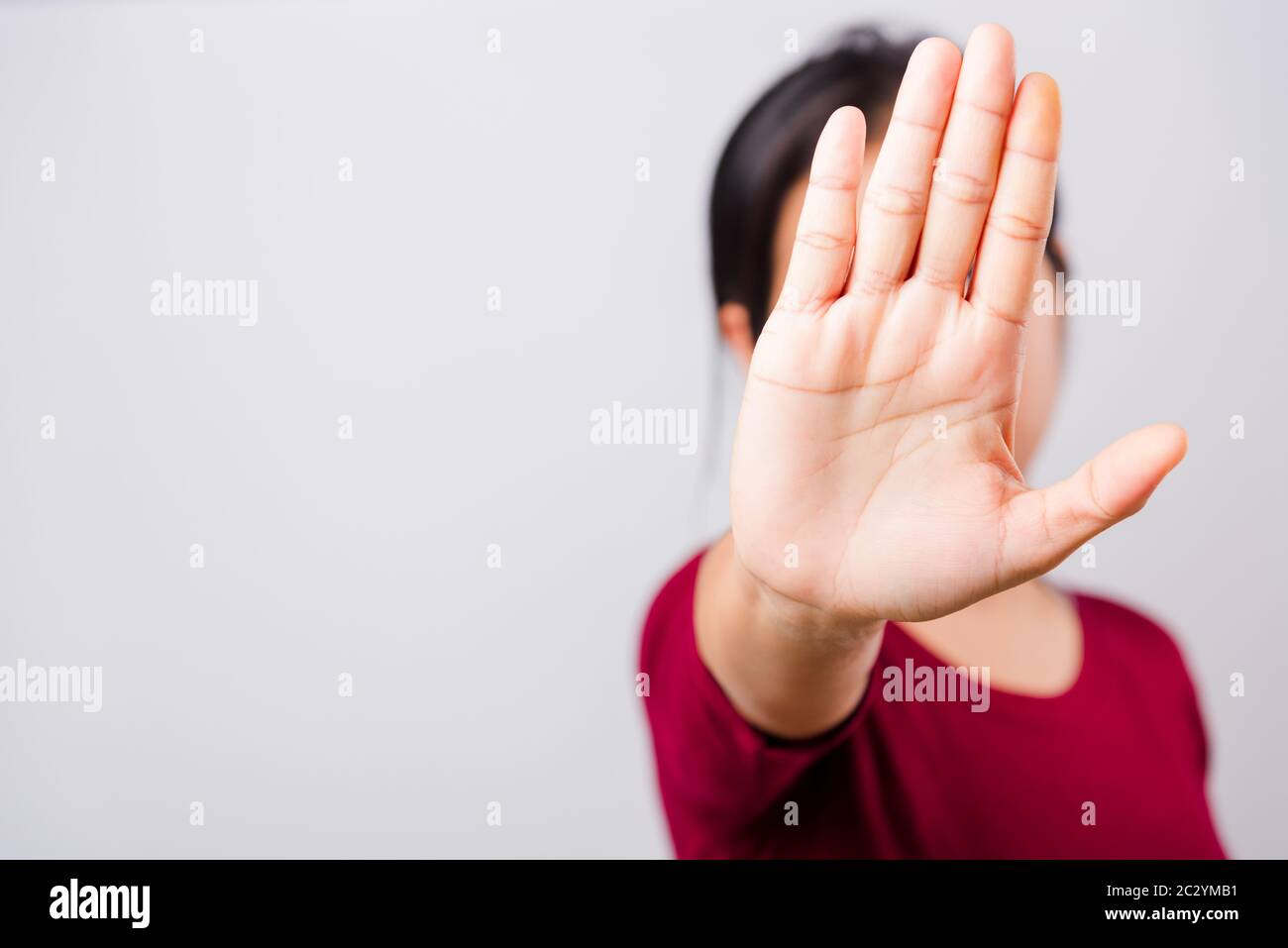 Asian bella donna prurito la sua mano distesa mostrando stop gesture viso anteriore, messa a fuoco sulla mano su sfondo bianco con spazio di copia Foto Stock