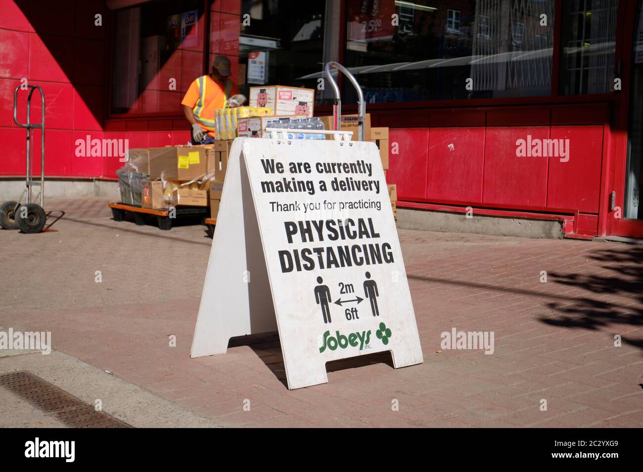 Cartello all'ingresso della drogheria Sobeys che chiede cure fisiche di allontanamento mentre la consegna del negozio sta avvenendo. Ottawa, Canada. 17 giugno 2020. Foto Stock