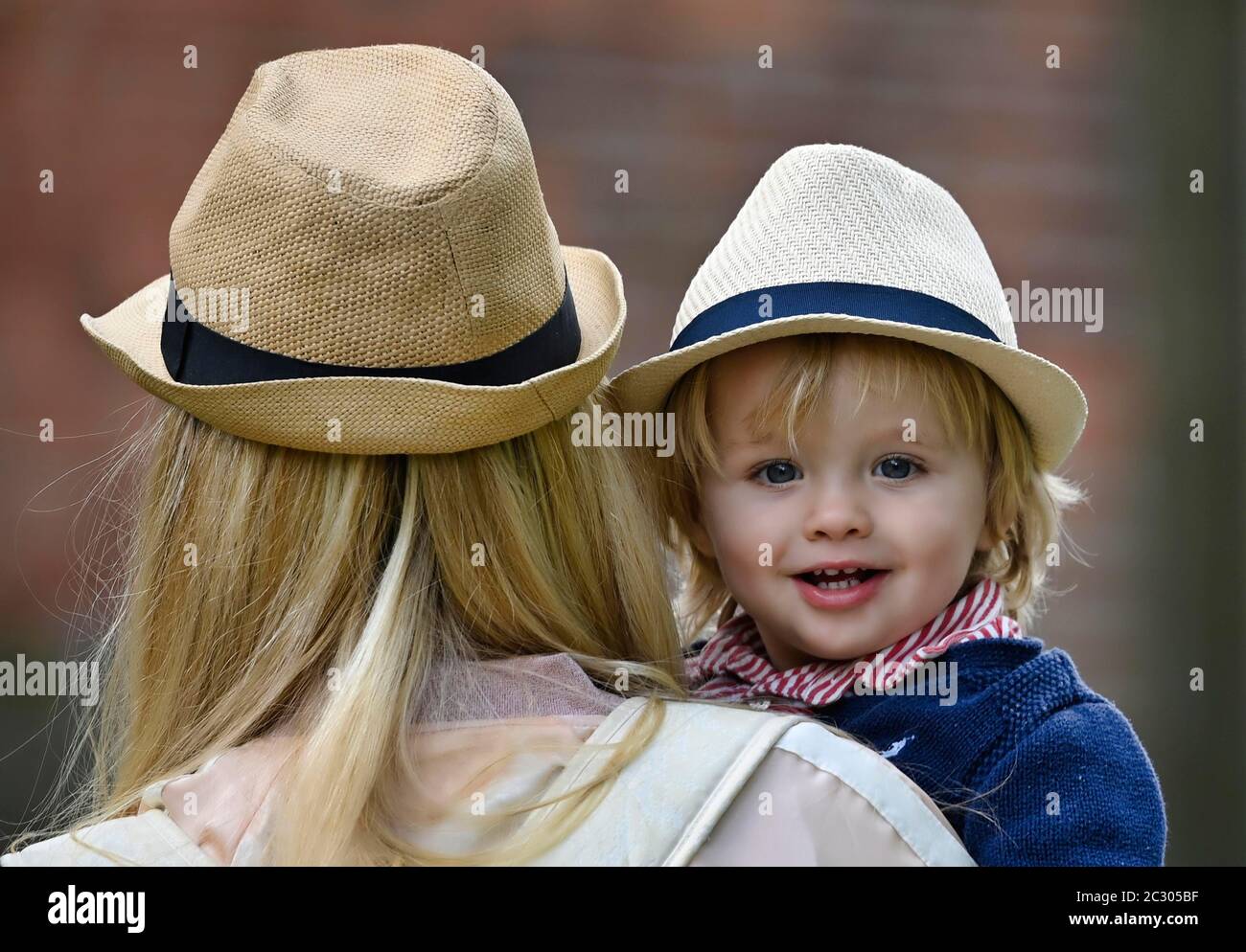 Madre che tiene il figlio, 19 mesi, in braccio, entrambi indossando cappello simile, Stoccarda Baden-Wuerttemberg, Germania Foto Stock
