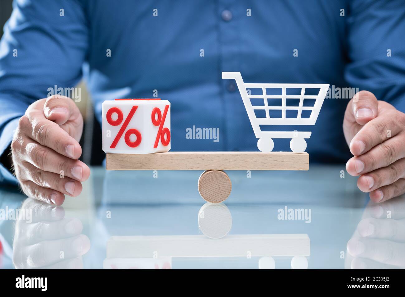 Equilibrio Di Protezione Della Mano Umana Tra Il Blocco Cubico Percentuale Bianco E Il Carrello Per Lo Shopping Su Seesaw Di Legno Foto Stock