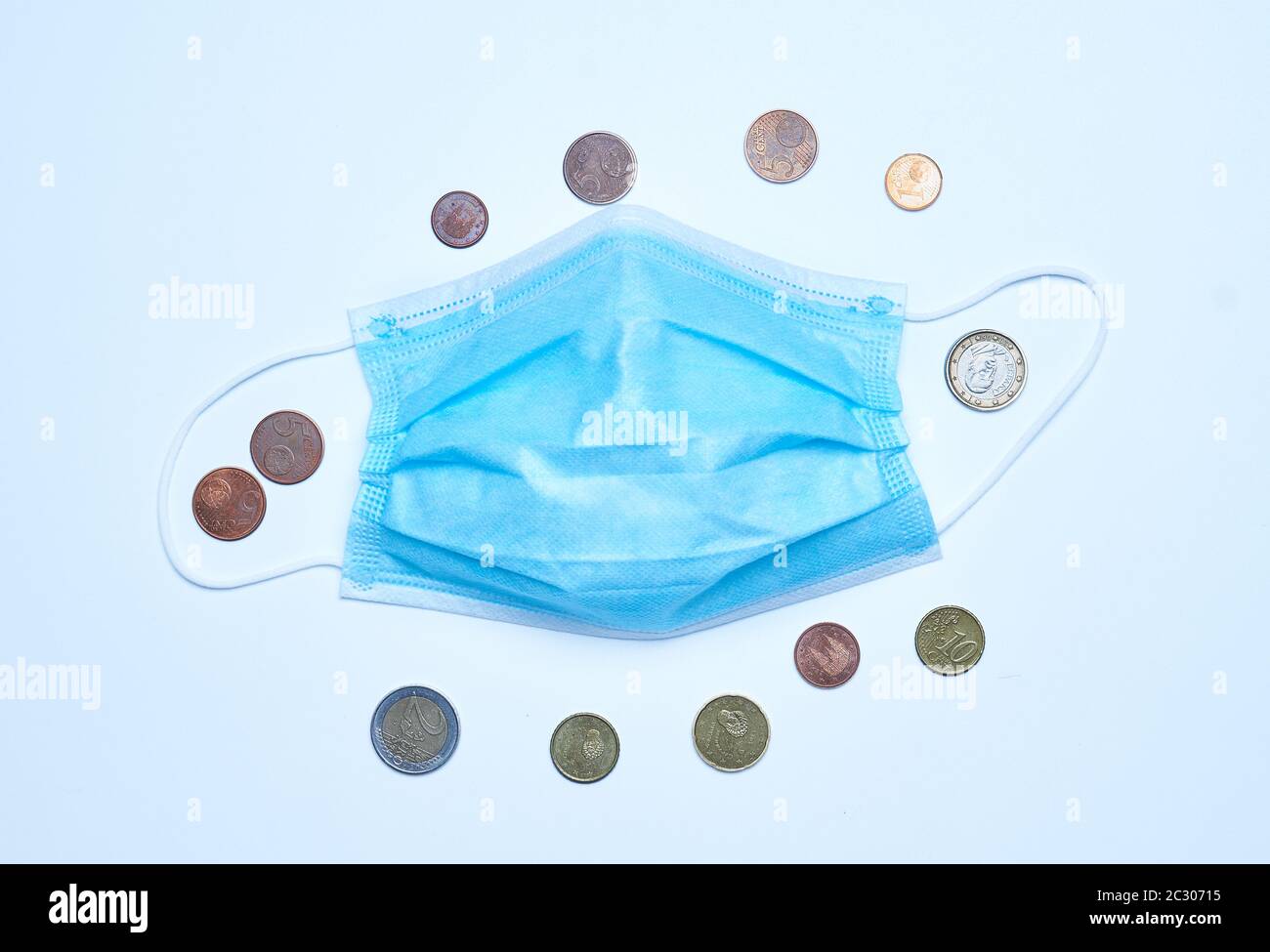 Un sacco di monete intorno a una maschera medica. Economia in tempi di coronavirus concetto. Foto Stock