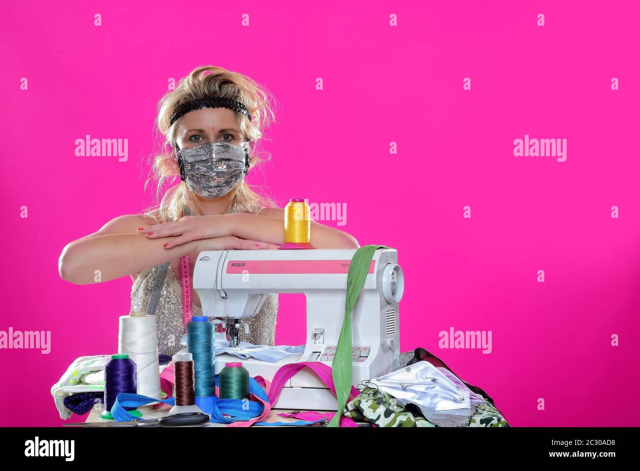 Giovane donna con macchina da cucire, maschere da cucire, Germania Foto Stock