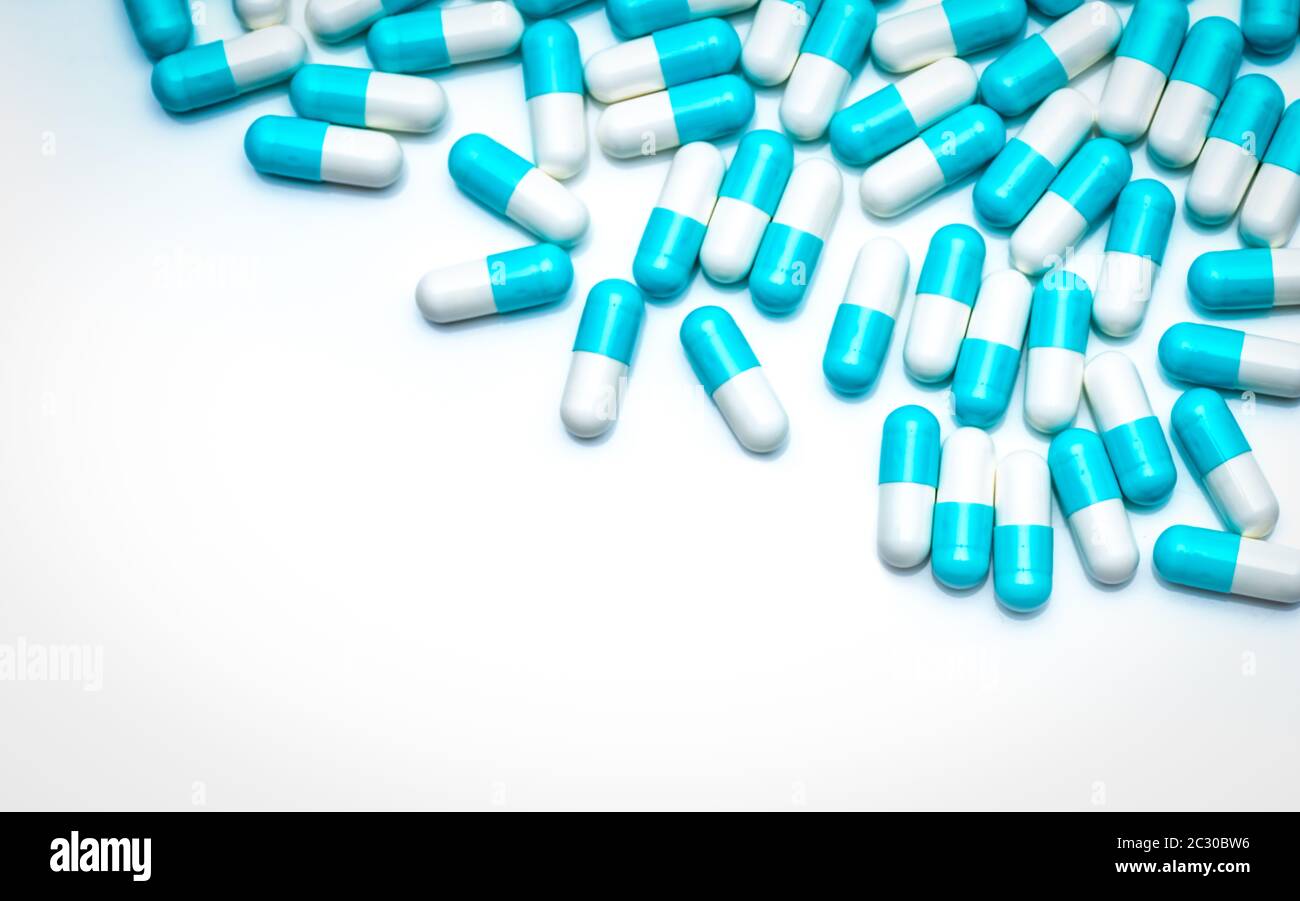 Capsule di antibiotico blu-bianco su sfondo bianco. Capsule pillole colorate per l'argomento sanitario. Industria farmaceutica. Residuo di farmaco antibiotico Foto Stock