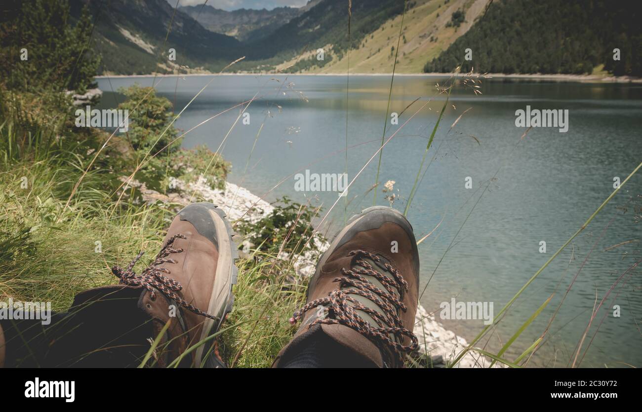 Hiker prendere una pausa seduto vicino al lago di Oule nella valle di Aure in Haute-Bigorre nel dipartimento degli alti Pirenei in Francia Foto Stock