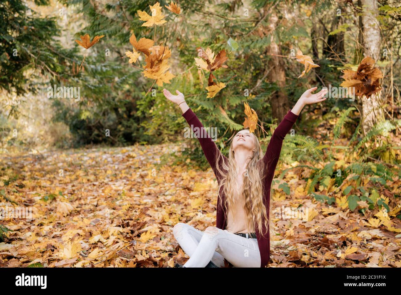 Vista di donna che gioca con foglie, Bainbridge Island, Washington, USA Foto Stock