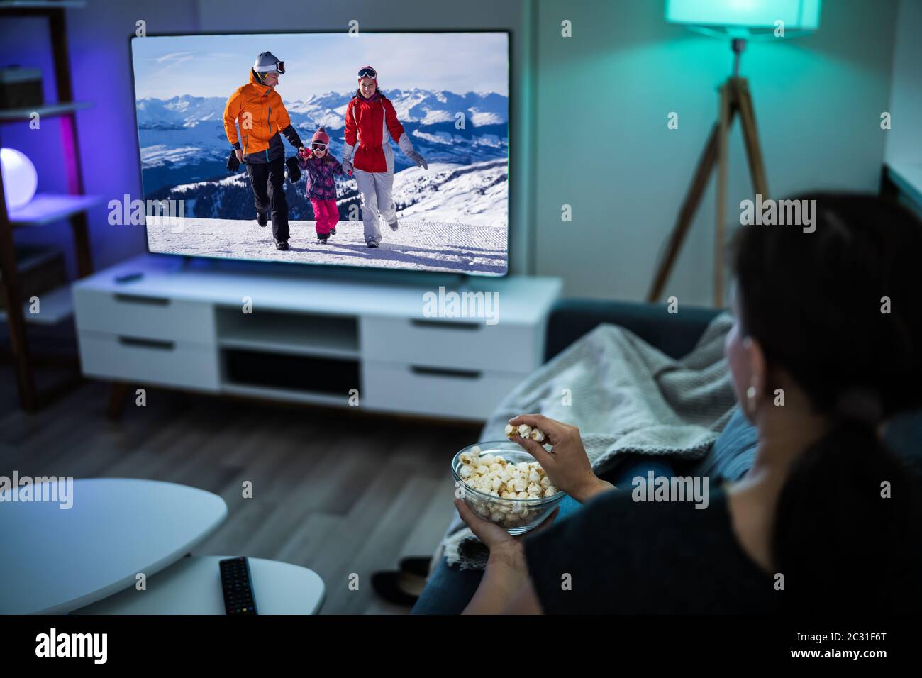 Donna che guarda la TV sul divano o sul divano. Guarda la televisione Foto Stock