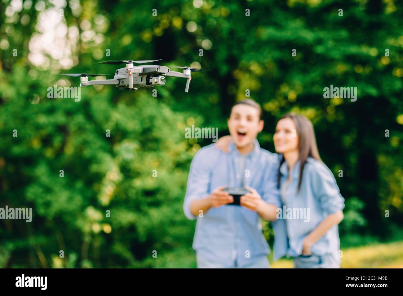 Ritratto di uomo e donna sta facendo funzionare il drone dal telecomando nel parco. L'uomo e la donna giocano con il quadricopter all'aperto. Foto Stock