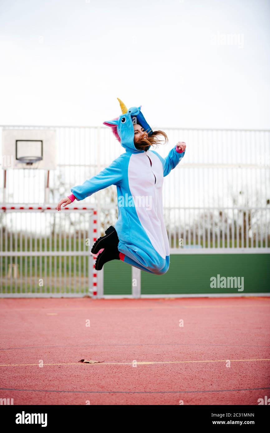 Giovane e bella donna che indossa il turchese unicorn onesie in ambiente urbano Foto Stock