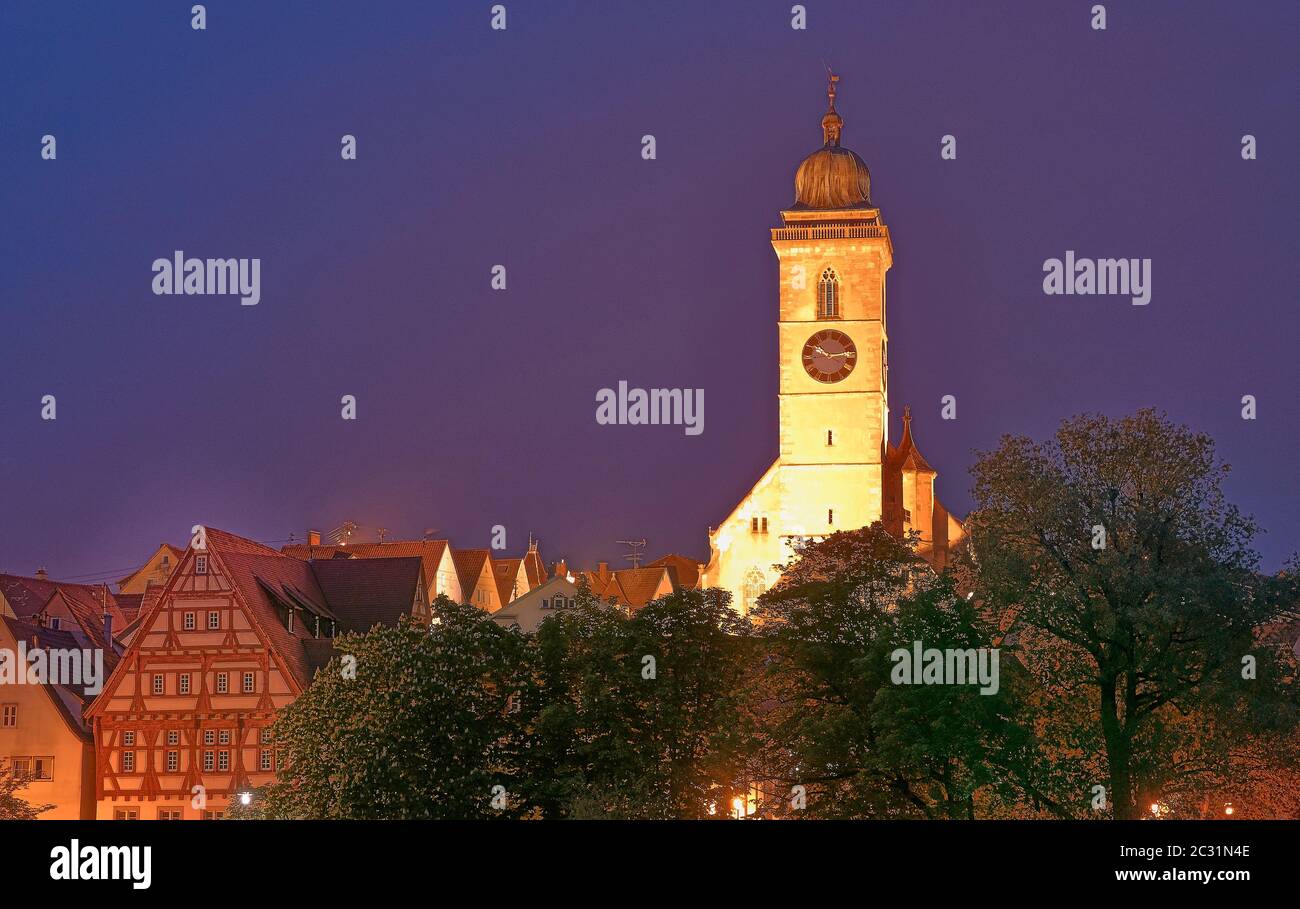 Laurentius chiesa a Nuertingen, torre gialla e cielo viola, alberi verdi in primo piano. Germania. Foto Stock