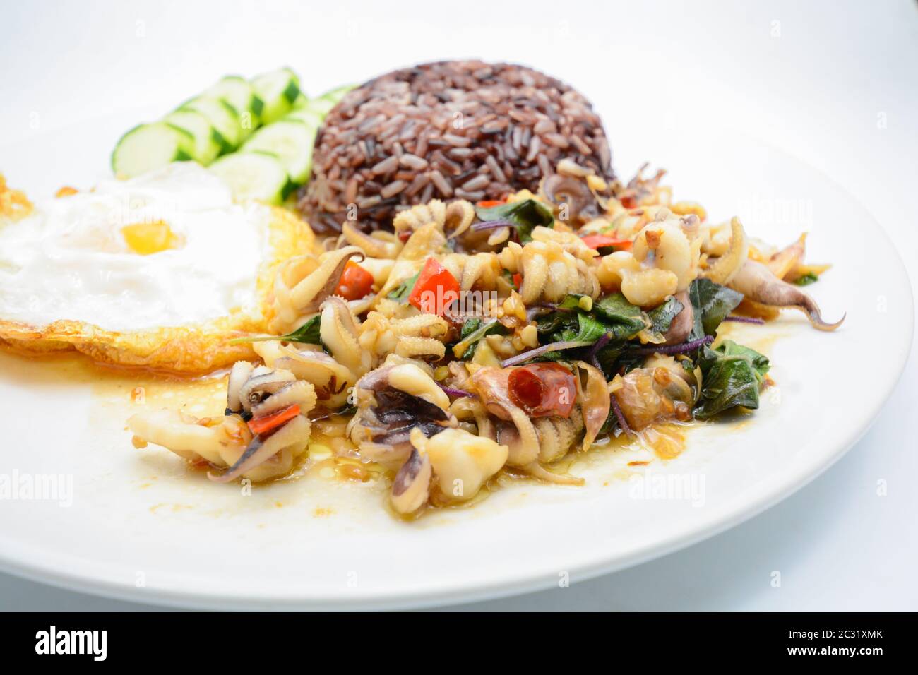 Piccante, soffritto di calamari fritti con foglie di basilico e peperoncino, uova sunnite con il lato alto, servite con riso marrone. È Foto Stock