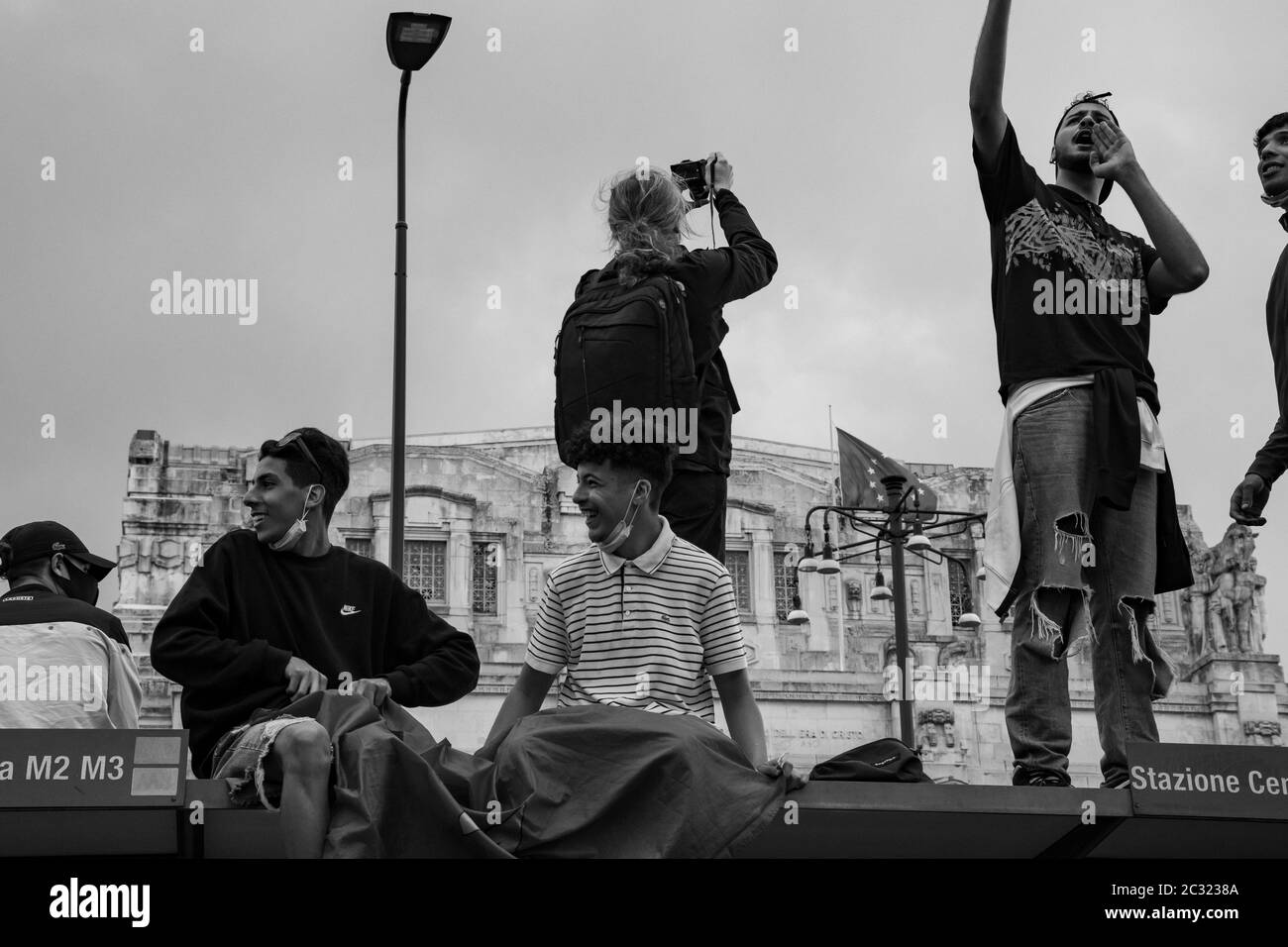 Gli amici stanno chiacchierando e ridendo mentre una donna sta scattando la foto davanti alla stazione centrale di Milano durante l'assemblea di protesta in solidarietà con BLM. Foto Stock