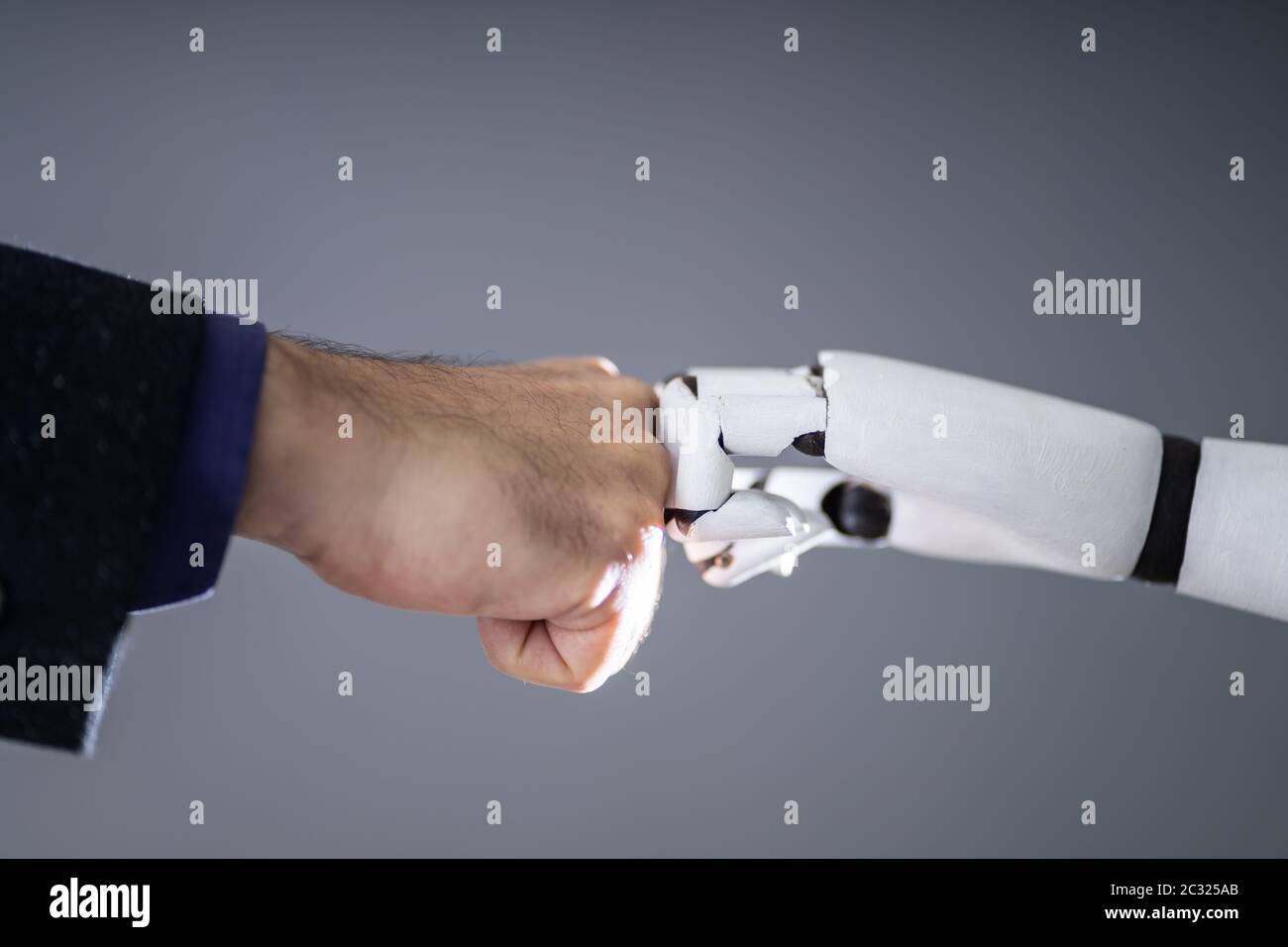 Il robot e la mano umana facendo Fist Bump su sfondo grigio Foto Stock