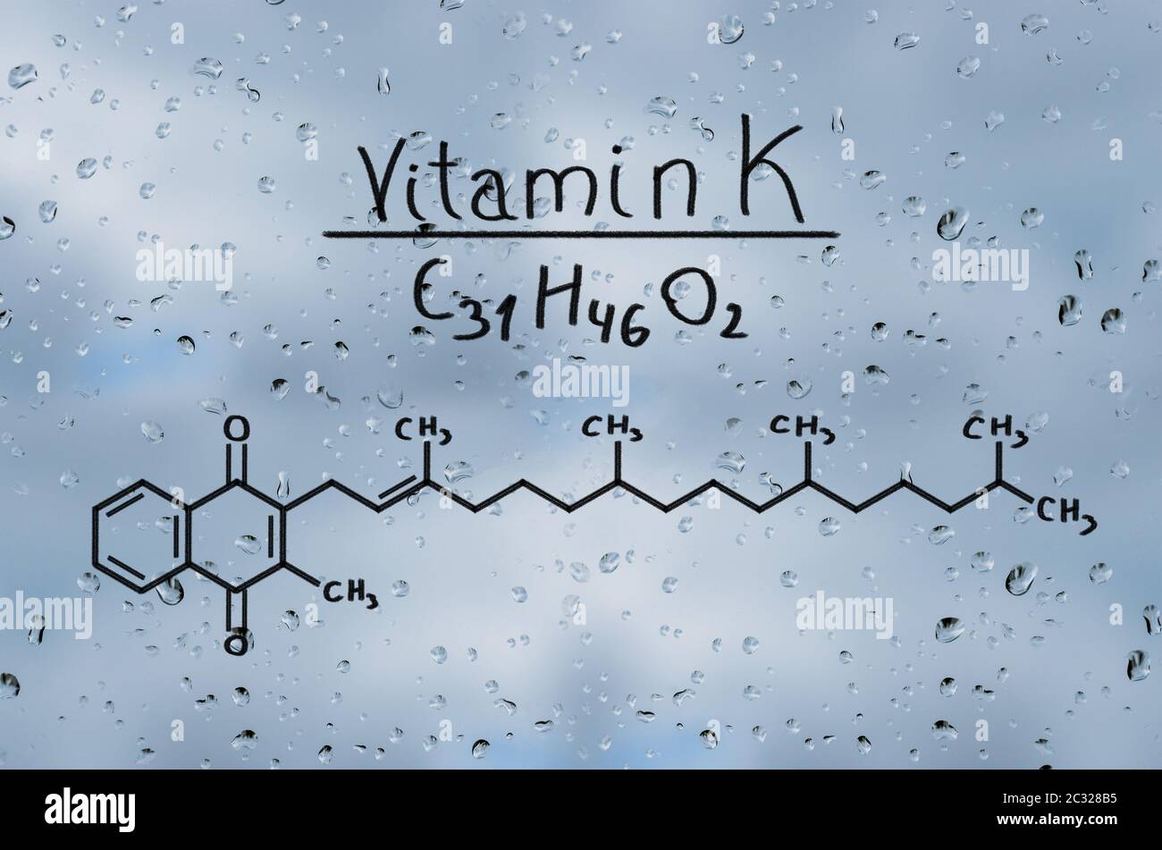 Il modello strutturale della vitamina K sul vetro con gocce di pioggia. Foto Stock