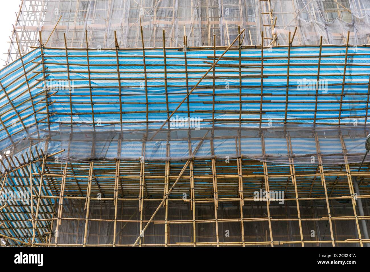 Impalcature di bambù con rete di sicurezza al grattacielo Sito in costruzione Foto Stock