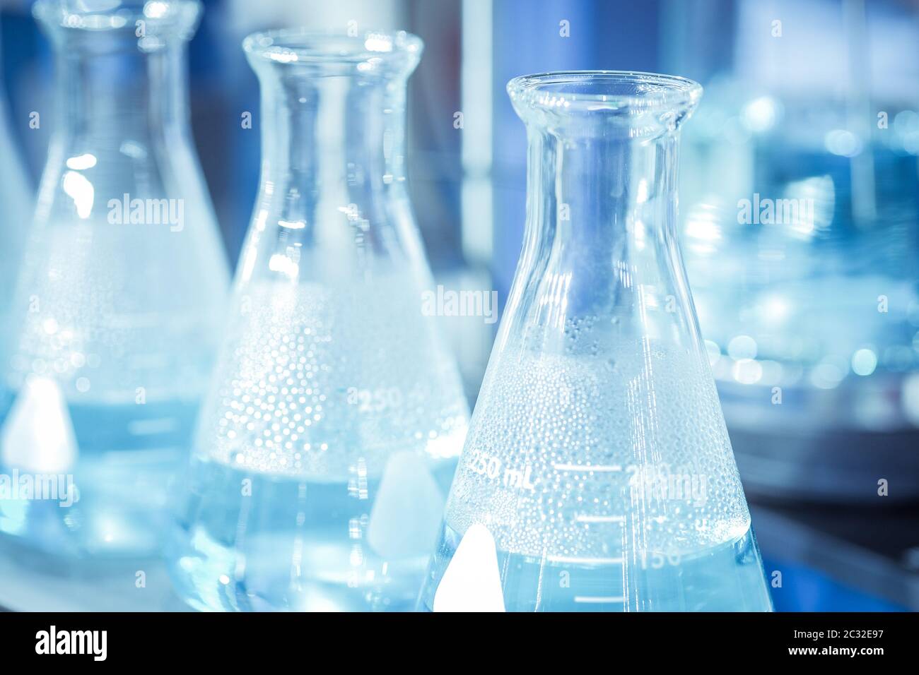 Provetta per analisi chimiche in vetreria con soluzione chimica su sfondo di colore blu Foto Stock